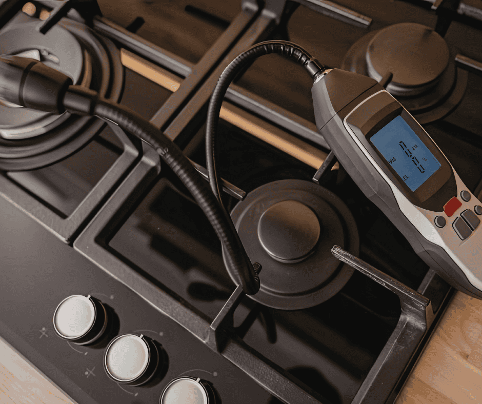Electronic gas leak detector testing a residential gas stove for potential gas leaks